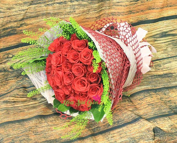 Bó hoa là sự kết hợp của vẻ đẹp quyến rũ của những bông hồng đỏ nổi bật trên nền lá xanh